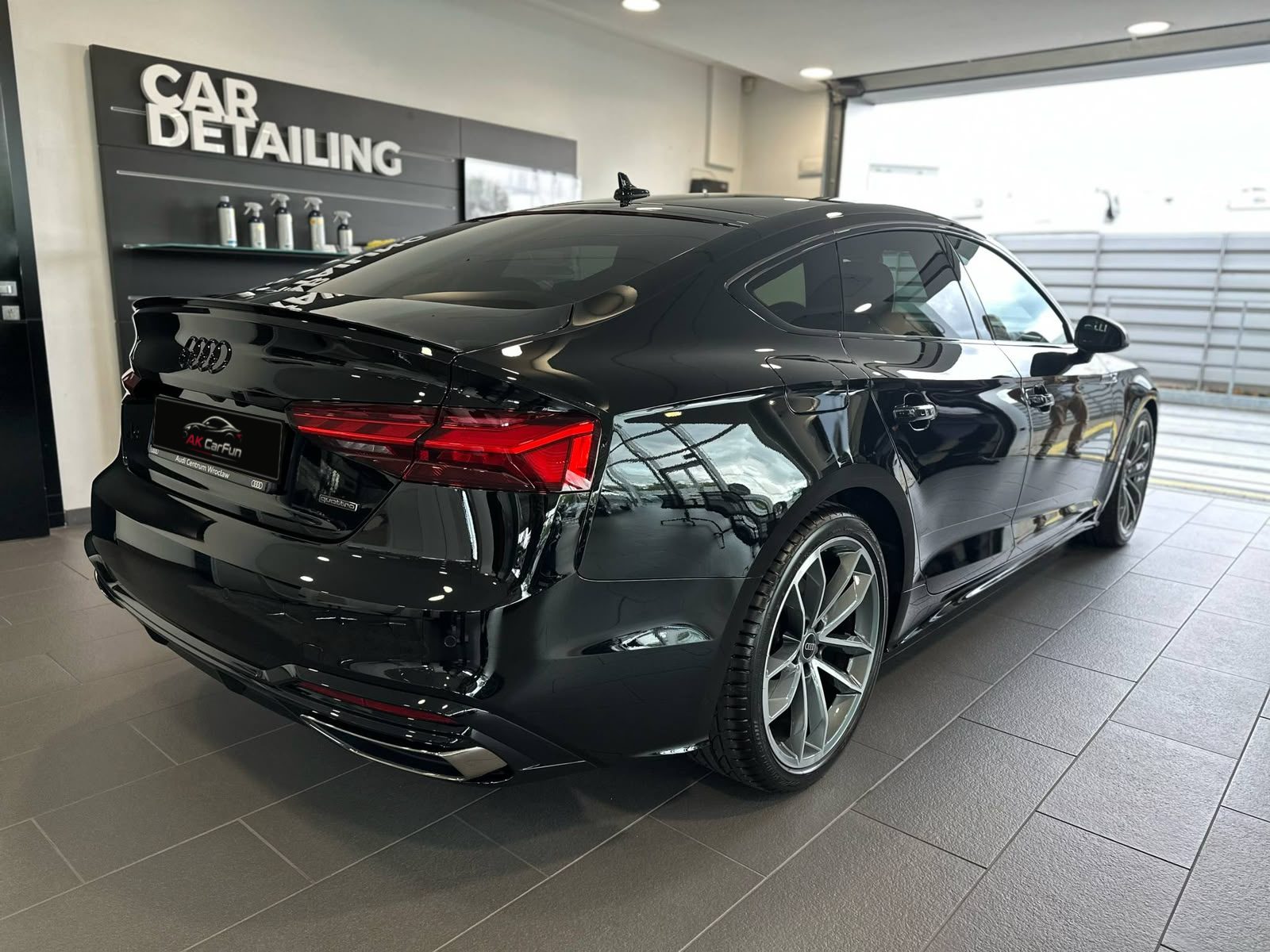 Tył czarnego Audi A5 Sportback w studiu detailingu, z tablicą AK CarFun