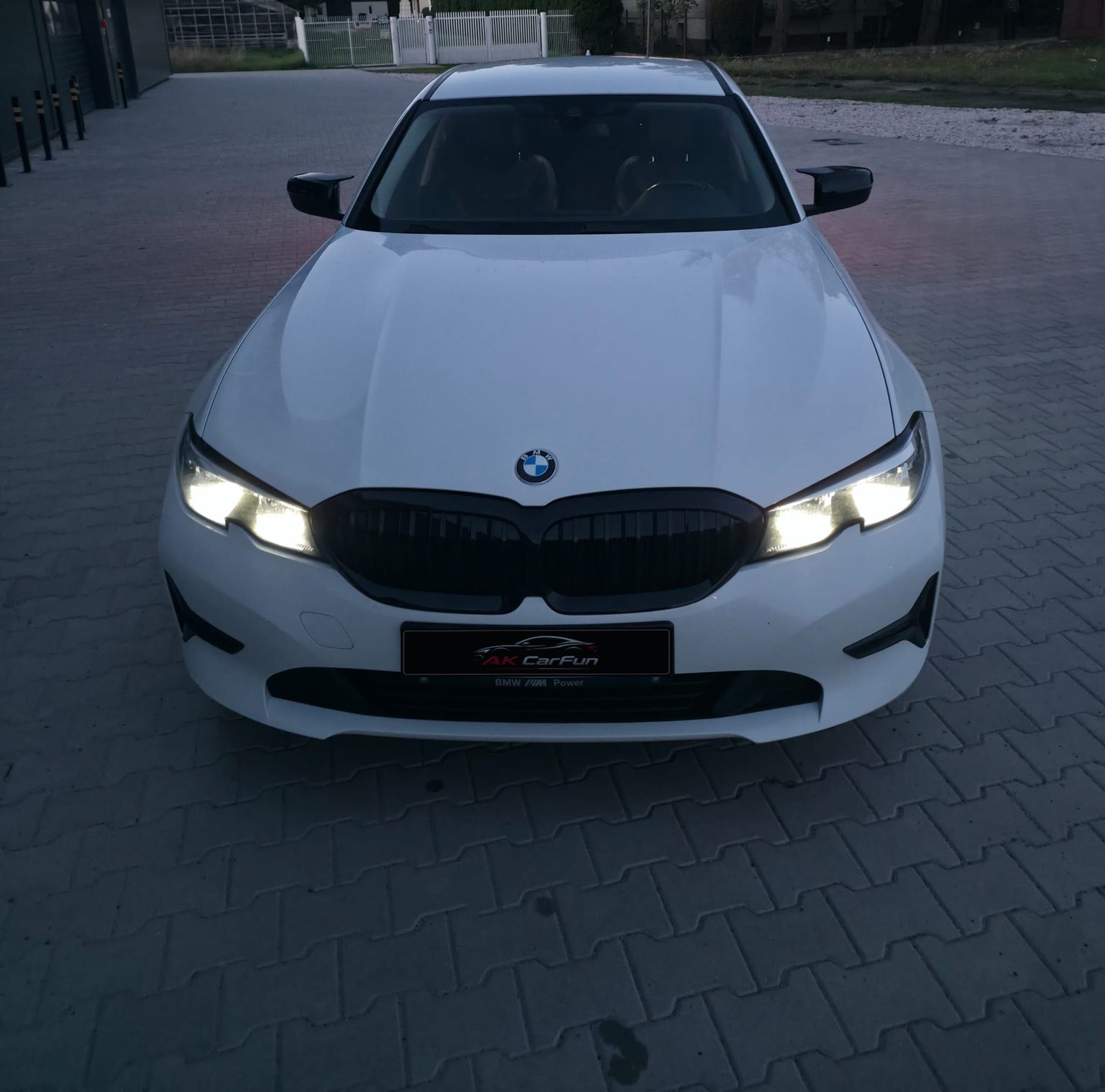 Białe BMW 318i G20 2020 z góry, od przodu, z włączonymi reflektorami
